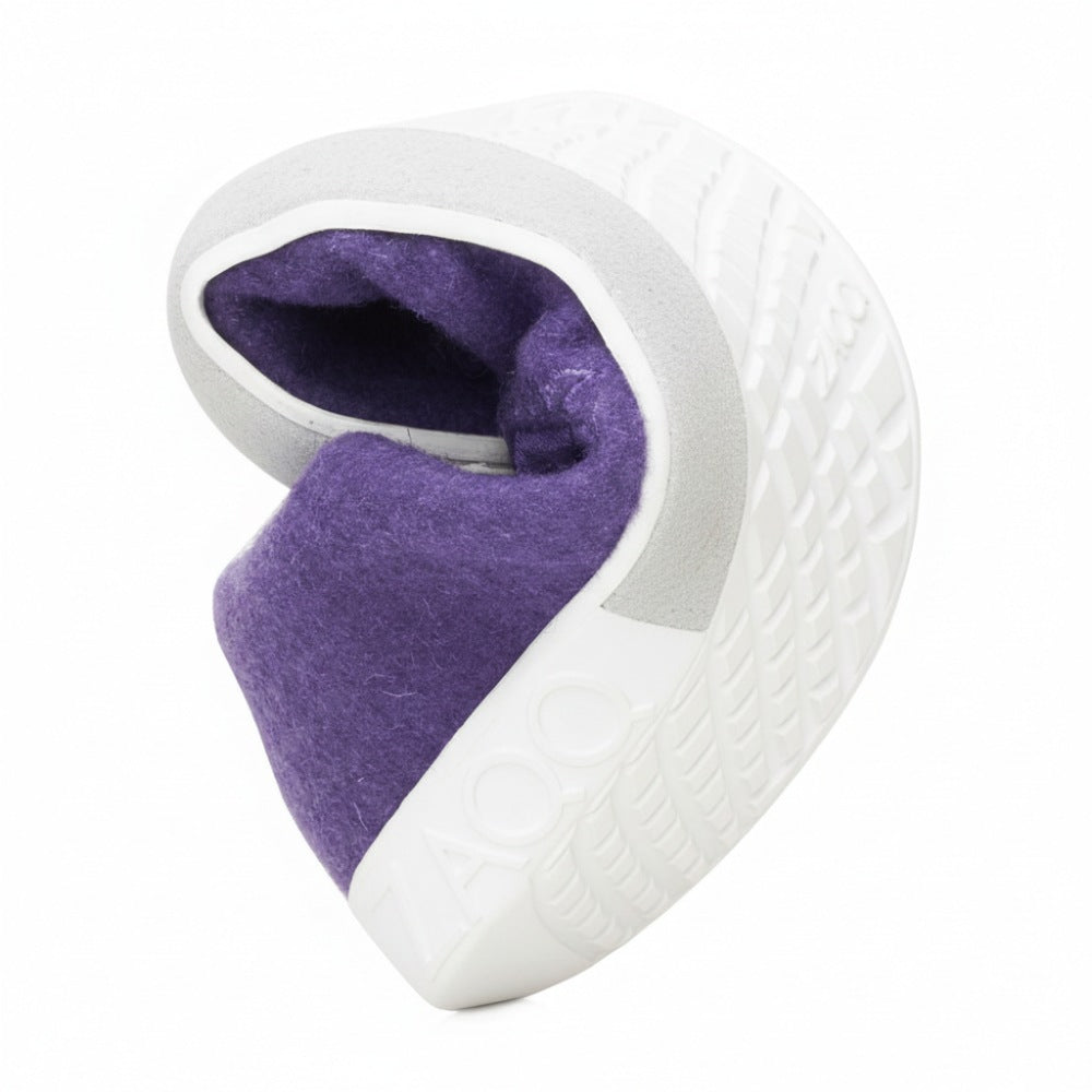 Wir präsentieren LIQE Purple von ZAQQ, eine kleine, aufwendig gestaltete Skulptur, die an einen Glückskeks erinnert. Sie hat eine strukturierte graue Außenseite mit einer leuchtend violetten Innenseite und detaillierte Muster, die an den Griff der Barfußsohle erinnern, sowie den Text „ZAOO“.