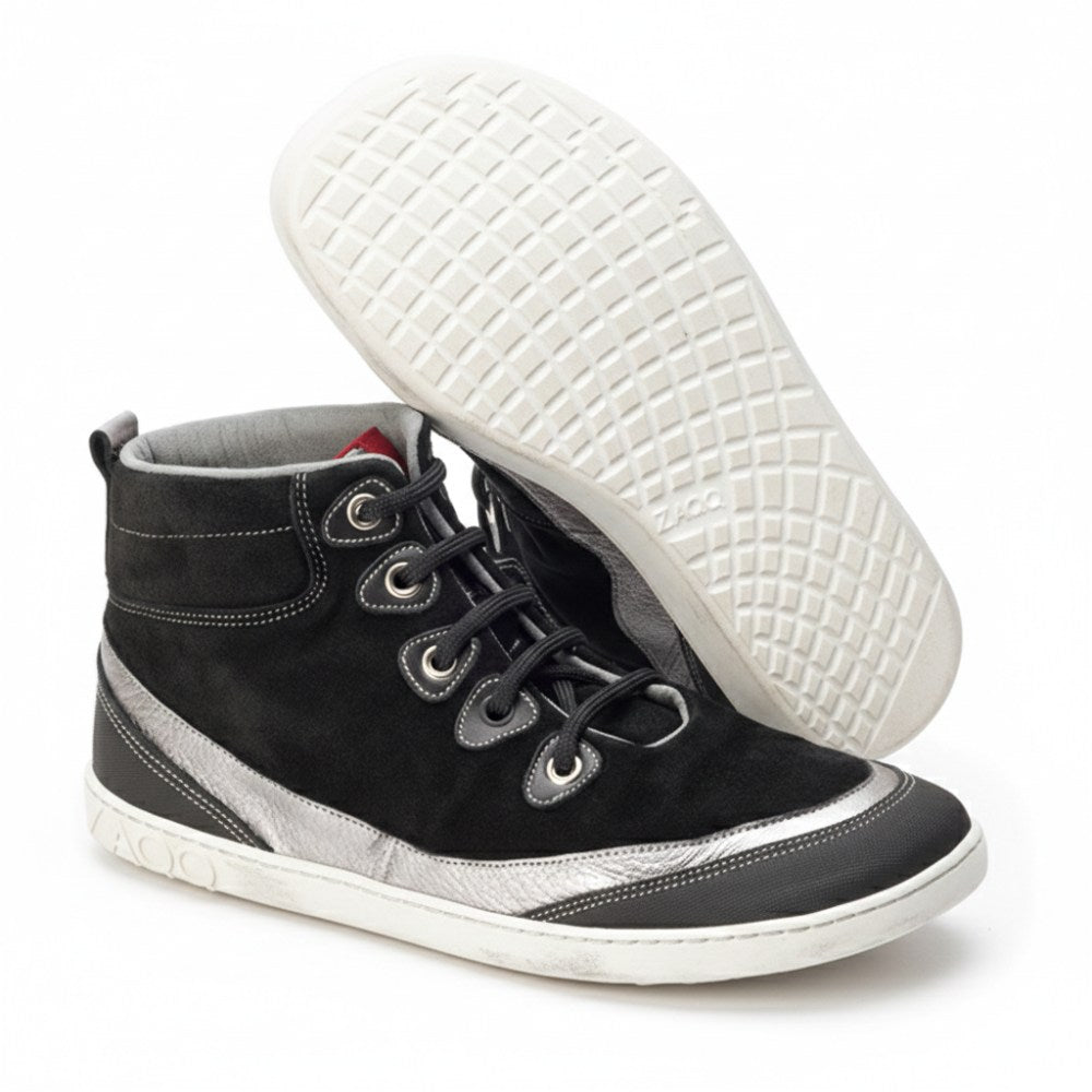 Ein Paar schwarze High-Top-Sneakers FRANQY von ZAQQ haben ein Obermaterial aus schwarzem Wildleder, schwarze Schnürsenkel und metallisch-silberne Akzente. Die weißen Sohlen zeigen ein Gittermuster mit dem Markennamen ZAQQ, der deutlich hervorgehoben ist. Ein Sneaker steht aufrecht, während der andere geneigt ist, um sein kompliziertes Sohlendesign hervorzuheben.