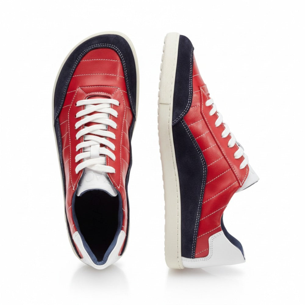 Zwei QAMPION Navy Red Sneaker von ZAQQ sind mit rotem Nappaleder, blauem Wildleder und weißen Akzenten versehen. Ein Schuh ist von oben abgebildet, während der andere von der Seite gezeigt wird, was die weißen Schnürsenkel und eine strukturierte graue Sohle hervorhebt.