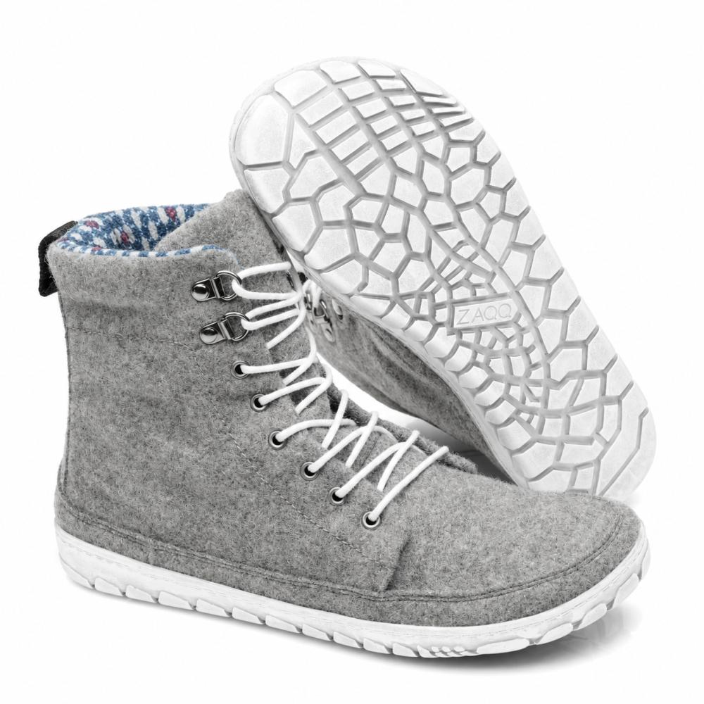 Ausgestellt wird ein Paar QICE Grey High-Top-Sneakers von ZAQQ mit weißen Schnürsenkeln. Ein Schuh steht aufrecht, während der andere angewinkelt ist, um die strukturierte, gemusterte Outdoorsohle hervorzuheben.