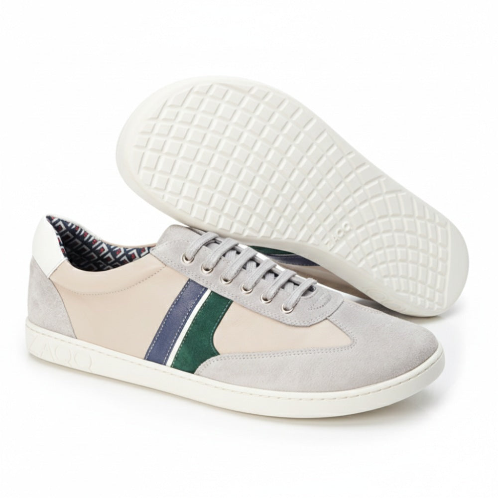 Die QLAUDE Grey Sneaker von ZAQQ zeichnen sich durch beige Akzente mit grünen und blauen Streifen aus und sorgen so für einen eleganten und dennoch lässigen Look. Ein Schuh steht aufrecht, während der andere seine Sneakersohle mit aufwendig geprägten kreisförmigen Mustern zeigt, die diesem Herren-Barfußschuh ein einzigartiges Flair verleihen.