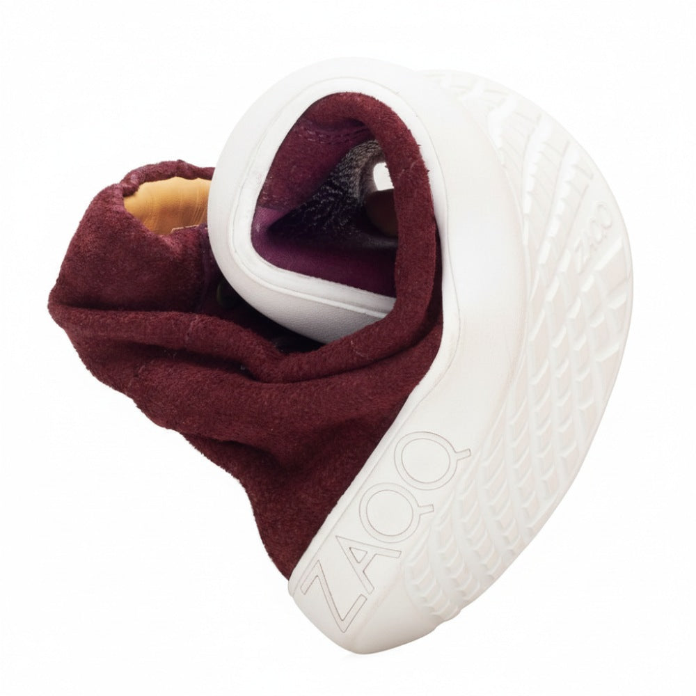 Ein flexibler, kastanienbrauner Sneaker ist zu einer kompakten Spirale gedreht und enthüllt seine Sohle mit dem ZAQQ-Logo. Das QORE High Mazarine-Design zeigt seine Flexibilität und einzigartige Konstruktion und kombiniert gekonnt Verlours- und Glattleder für zusätzlichen Stil.