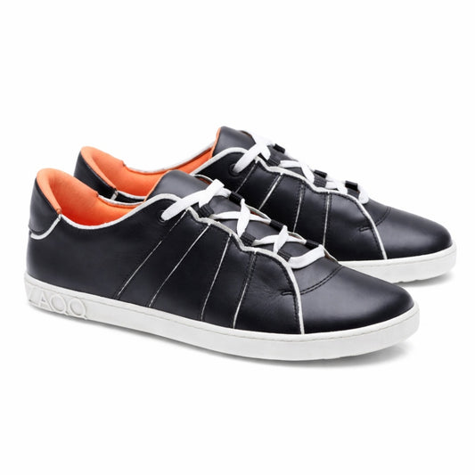 Ein Paar QQQ Low Black White-Sneaker von ZAQQ mit außergewöhnlichem Tragekomfort, gefertigt aus schwarzem Leder mit auffälligen weißen Schnürsenkeln und Sohlen. Die Innenseite ist in einem leuchtenden Orange gehalten und wird durch dekorative weiße Nähte an den Seiten hervorgehoben. Die Schuhe sind so positioniert, dass sie sowohl von der Seite als auch von vorne gut aussehen.