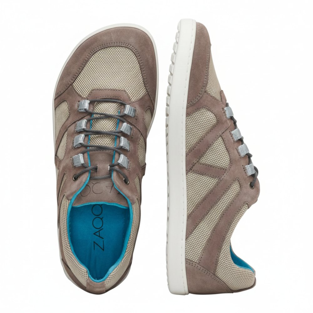 Die QUSQO Taupe Freizeitschuhe von ZAQQ zeichnen sich durch ein Design mit beigefarbenem, atmungsaktivem Netzgewebe, Akzenten aus taupefarbenem Wildleder, grauen Schnürsenkeln und einer blauen Innensohle aus. Das ZAQQ-Branding ist sowohl auf der Sohle als auch auf der Innensohle sichtbar. Ein Schuh wird aufrecht präsentiert, während der andere auf der Seite liegt und Bewegungsfreiheit für ultimativen Komfort bietet.