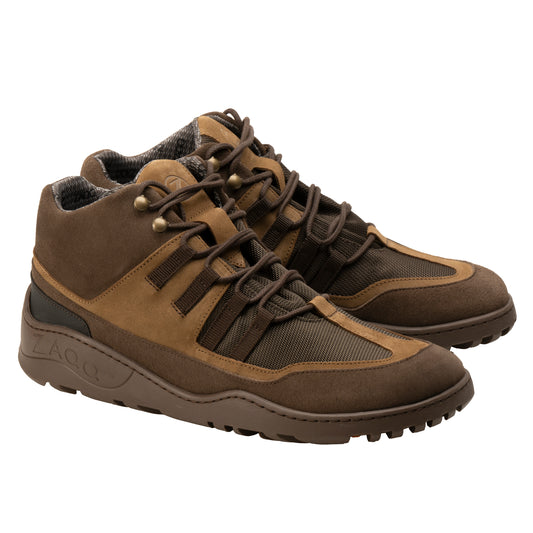 Wir präsentieren die braunen wasserdichten SQOUT-Stiefel von ZAQQ mit robuster ZAQQ TERRA-Sohle. Diese wasserdichten Wanderschuhe haben eine Schnürung vorne, eine Kombination aus Veloursleder und Mesh-Materialien sowie eine gepolsterte Knöchelstütze. Sie werden vor einem schlichten weißen Hintergrund präsentiert.