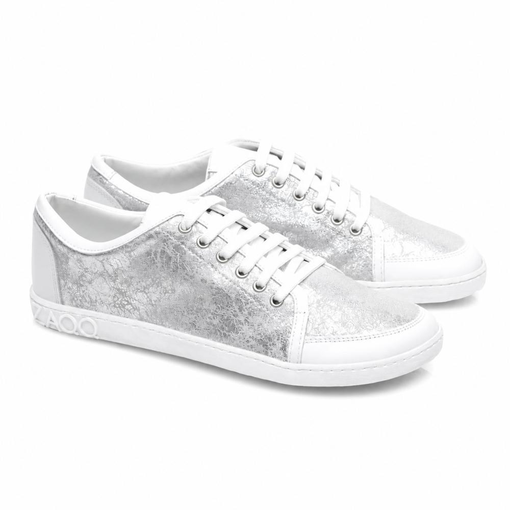 Predstavujeme TIQQ Silver White od ZAQQ: Pár štýlových tenisiek z kvalitnej nappy kože s výraznou kovovo-striebornou textúrou a bielymi podrážkami. Tieto tenisky sú vybavené žiarivo bielymi šnúrkami, ozdobnými švami a výrazným detailom 4000 na boku podrážky.